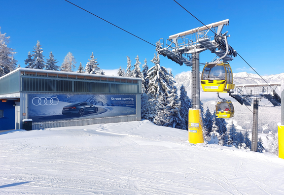 OOH-Werbefläche im Skigebiet Hauser Kaibling in den Alpen: großformatige Audi-Werbung an der Liftstation vor verschneiter Bergkulisse