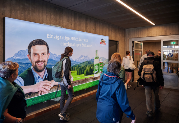 Wanderer, die in Garmisch die Bergbahn zum Aufstieg nutzen mit markanter Werbefläche