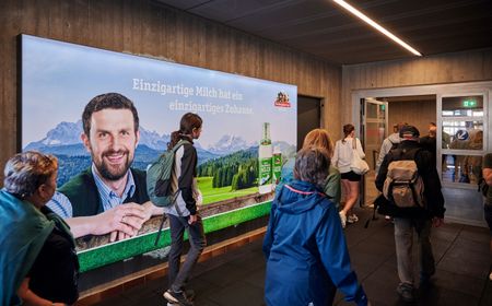 Wanderer, die in Garmisch die Bergbahn zum Aufstieg nutzen mit markanter Werbefläche