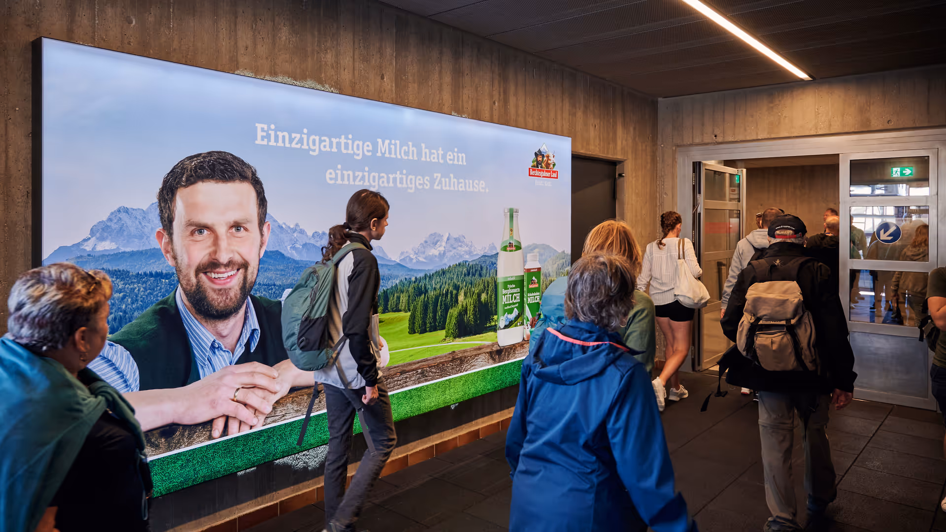Wanderer, die in Garmisch die Bergbahn zum Aufstieg nutzen mit markanter Werbefläche